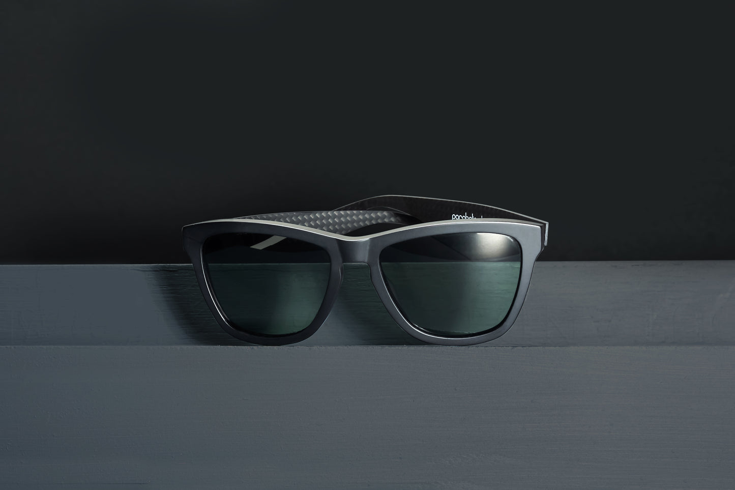 Parabolica Silverstone carbon fiber sunglasses, matte black with green polarized lenses, studio.